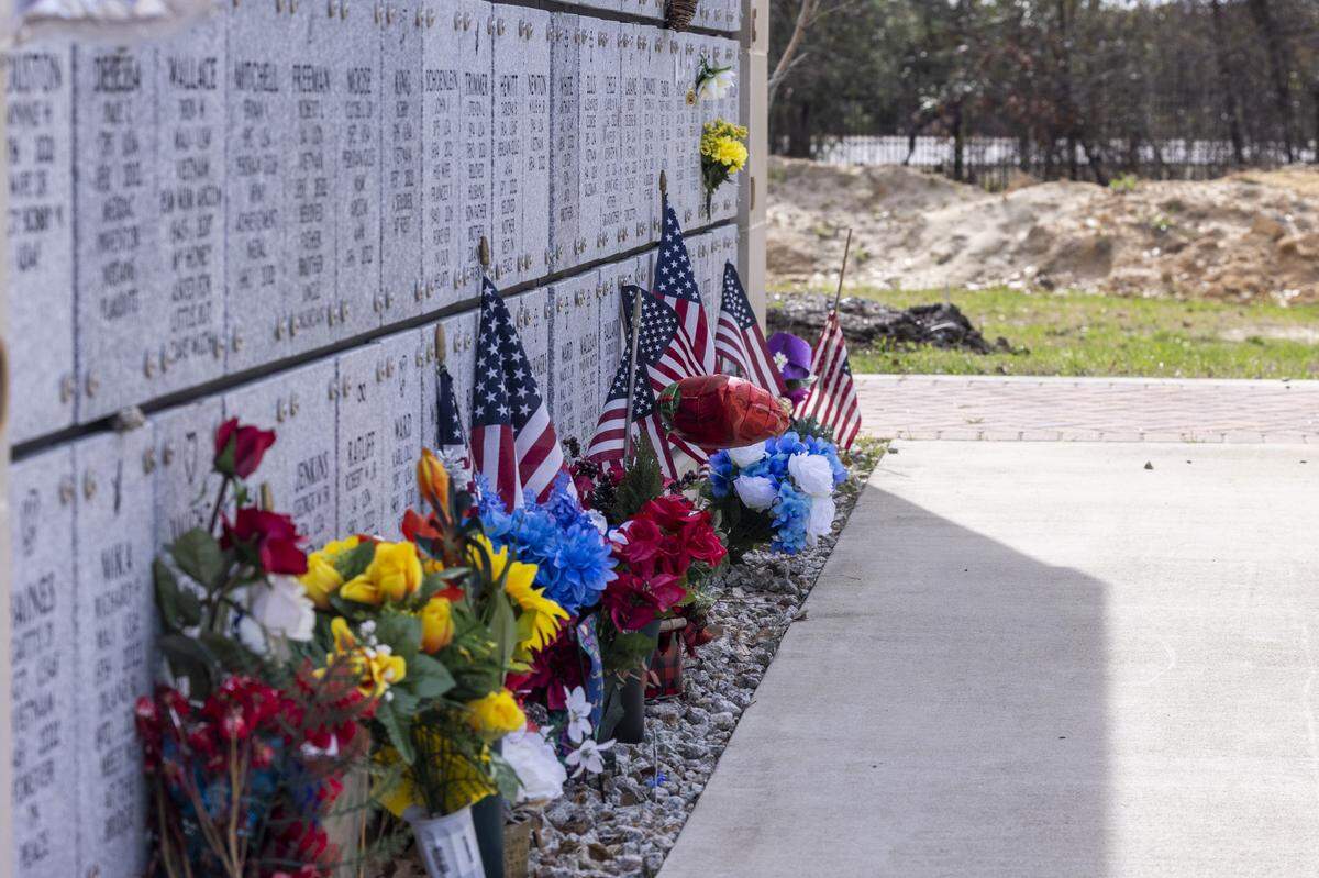 Flowers and flags line the base of a mausoleum at Sandhills State Veterans Cemetery in Spring Lake Tuesday, Feb 21, 2022. North Carolina’s four state-owned veterans cemeteries are behind on maintenance and are short-staffed