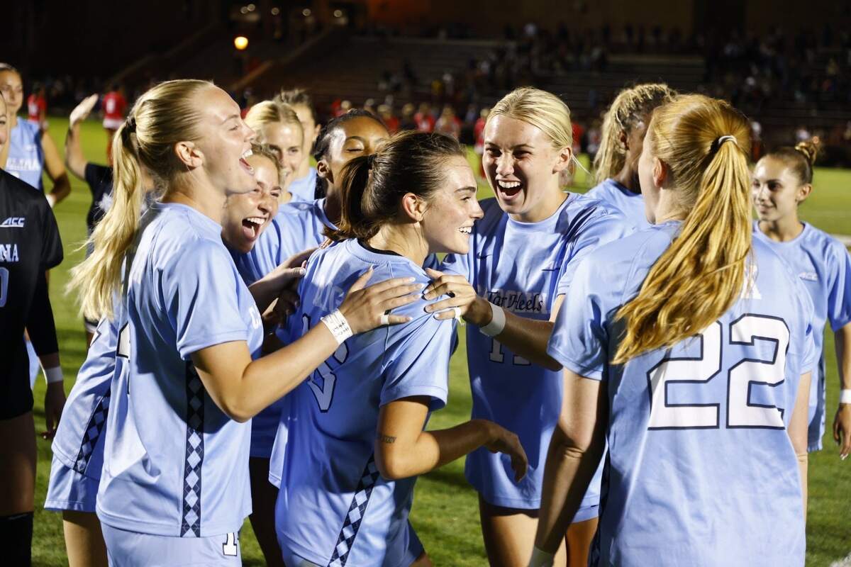 Olivia Migli is surrounded by her celebrating UNC Tar Heels teammates during a 2024 game. Migli transferred from Duke to UNC last summer.