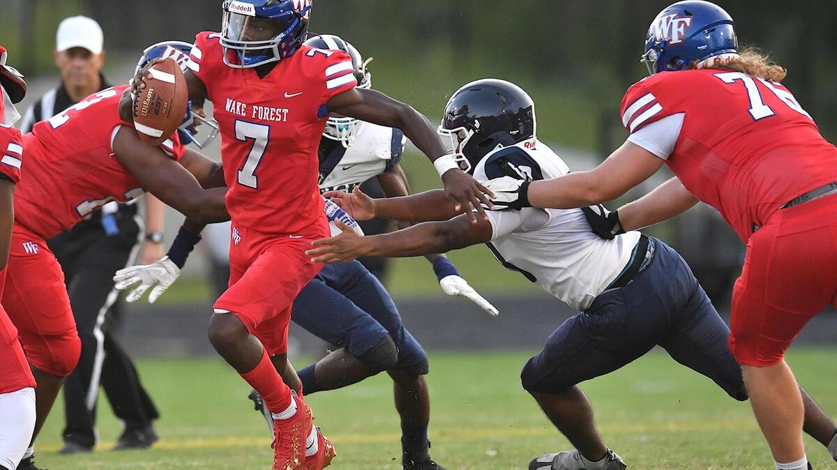 Wake Forest quarterback Kavon Simmons (7) scrambles for yardage away from South East Raleigh’s Amed Melendez (50) during the first half. The Southeast Raleigh Bulldogs and the Wake Forest Cougars met in a non-conference game in Wake Forest, N.C. on September 1, 2023.