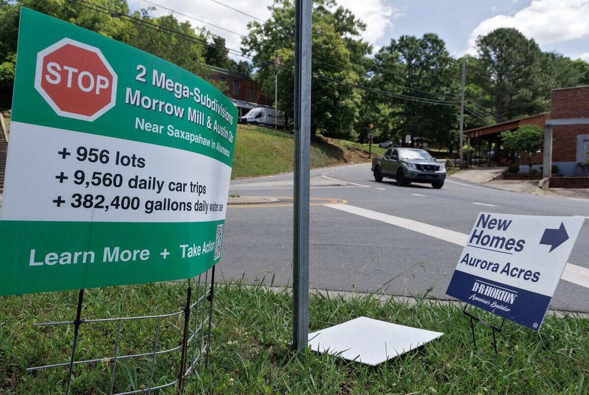 A motorist drives in downtown Saxapahaw past roadside signs protesting two pending residential developments and the lack of Alamance County zoning on Thursday, May 28, 2026.