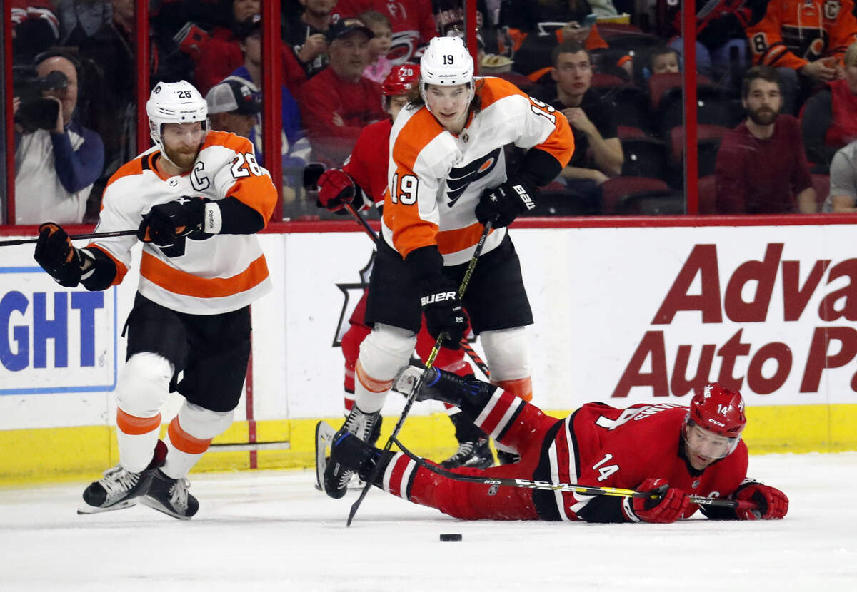 Carolina Hurricanes’ Justin Williams (14) hits the ice as he battles Philadelphia Flyers’ Claude Giroux (28) and Nolan Patrick (19) for the puck during the first period of an NHL hockey game in Raleigh, N.C. on Saturday, March 30, 2019. (