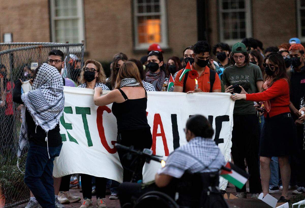 People raise a banner during a vigil held by the UNC chapter of Students for Justice in Palestine on Monday, Oct. 7, 2024, in Chapel Hill, N.C. The vigil was intended to honor those who have been killed during Israel’s counter-campaign against Hamas in the past year.