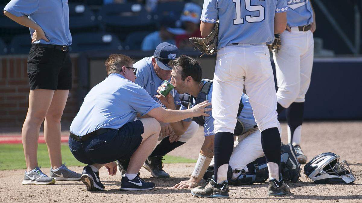 North Carolina coach Mike Fox and trainer Terri Jo Rucinski attend to catcher Cody Roberts after he was hit by a foul ball in the seventh inning against Duke on Sunday, May 13, 2018, at Durham Bulls Athletic Park in Durham, N.C.