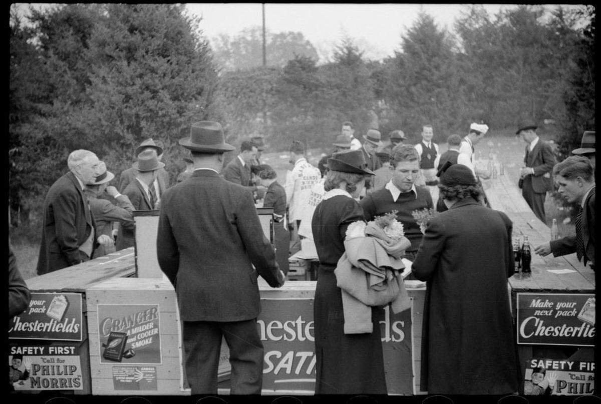 Fans buy concessions at a stand covered with cigarette advertising signs at the Duke-Carolina game in Durham, NC.