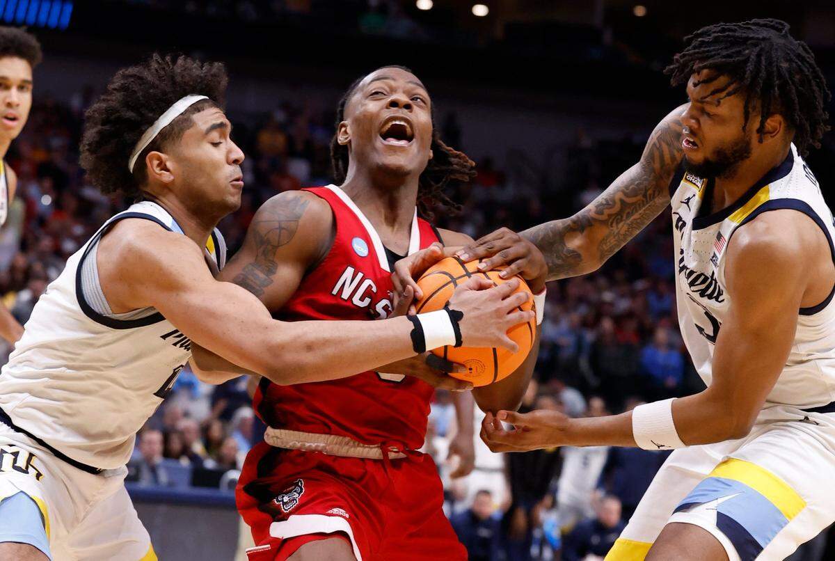 N.C. State’s DJ Horne (0) tries to drive by Marquette’s Stevie Mitchell (4) and David Joplin (23) during the second half of N.C. State’s 67-58 victory over Marquette in their NCAA Tournament Sweet 16 game at the American Airlines Center in Dallas, Texas, Friday, March 29, 2024.
