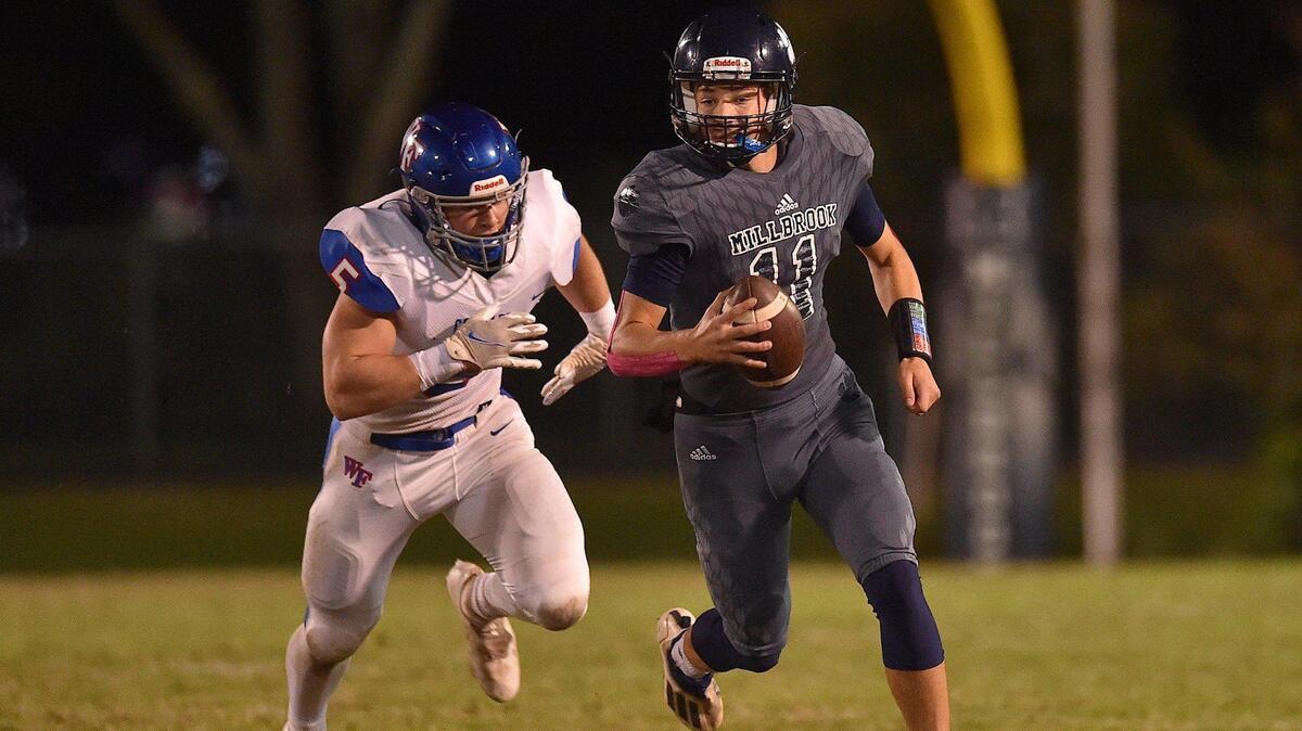 Millbrook quarterback Mason Fortune (11) runs for yardage ahead of Wake Forest’s Max Hines (5) during the first half. The Millbrook Wildcats and the Wake Forest Cougars met in a football game in Raleigh, N.C. on October 29, 2021.