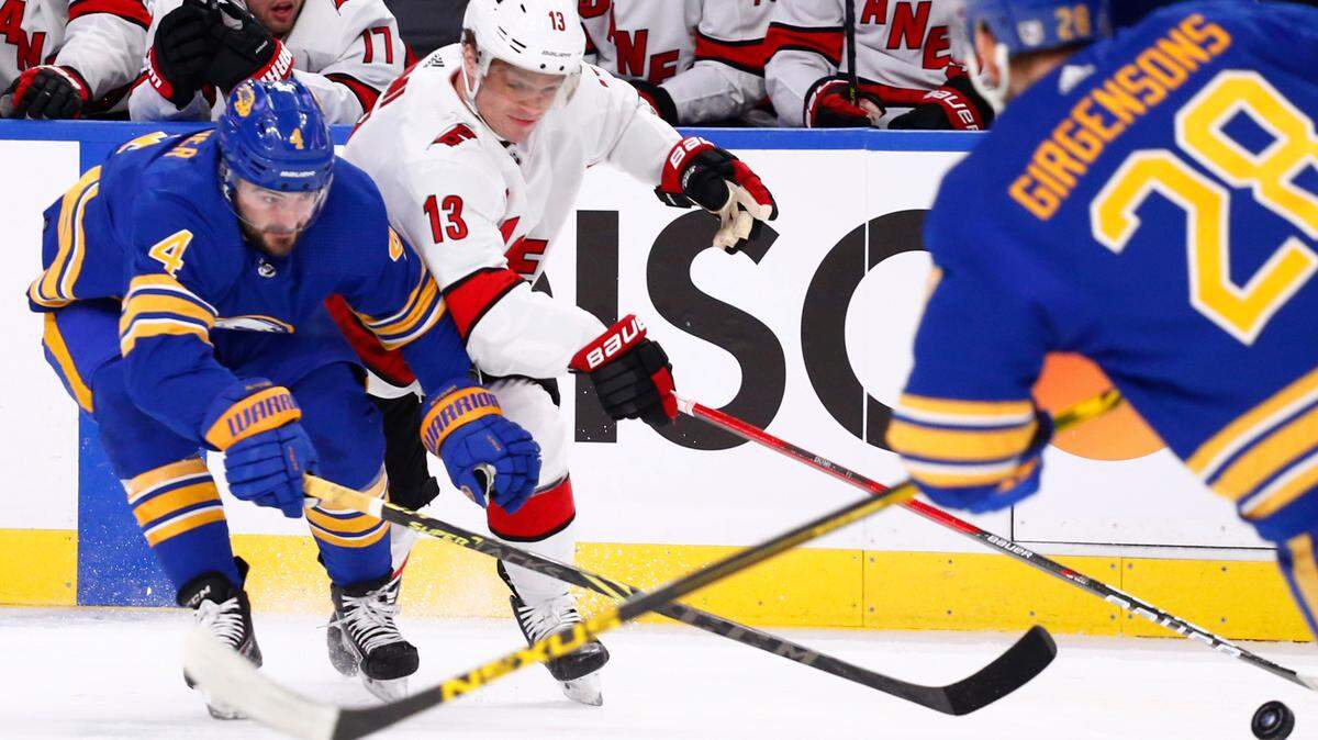 Carolina Hurricanes center Max Domi (13) checks Buffalo Sabres defenseman Will Butcher (4) during the first period of an NHL hockey game Tuesday, April 5, 2022, in Buffalo, N.Y. (AP Photo/Jeffrey T. Barnes)