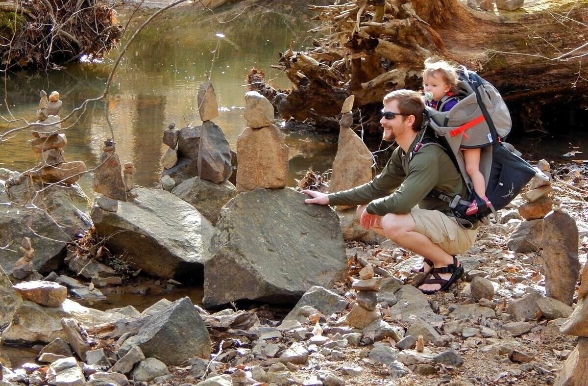A father stops to examine rock piles stacked on the banks of Bolin Creek while hiking with his child in this 2015 file photo.
