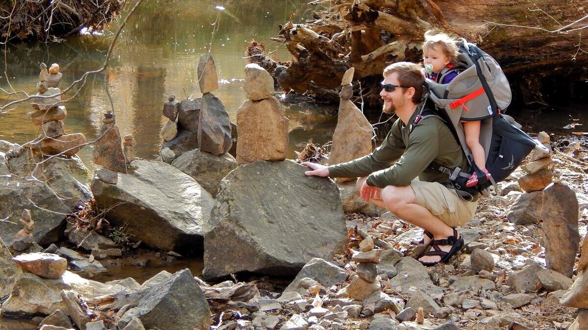 A father stops to examine rock piles stacked on the banks of Bolin Creek while hiking with his child in this 2015 file photo.