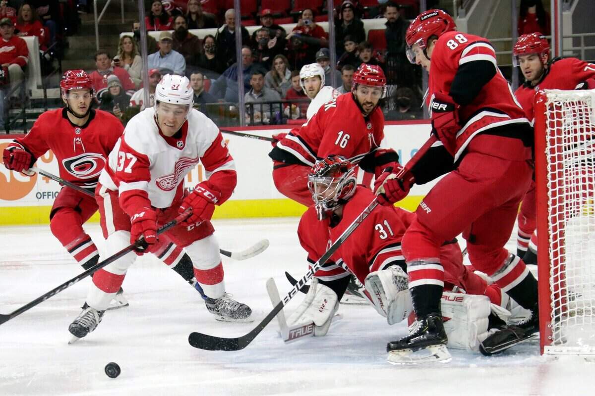 Detroit Red Wings center Carter Rowney (37) is defended by Carolina Hurricanes goaltender Frederik Andersen (31), center Vincent Trocheck (16) and center Martin Necas (88) as he works near the net during the first period of an NHL hockey game Thursday, Dec. 16, 2021, in Raleigh, N.C. (AP Photo/Chris Seward)