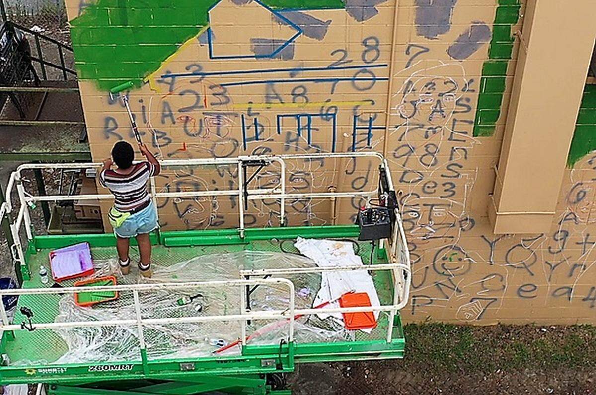 Raleigh artist Kiara Sanders works on the “African American Trailblazers” mural on South Merritt Mill Road in Chapel Hill. Sanders said it was a challenge to work on such a big canvas, but she learned a lot from the people who stopped to talk with her as she worked.