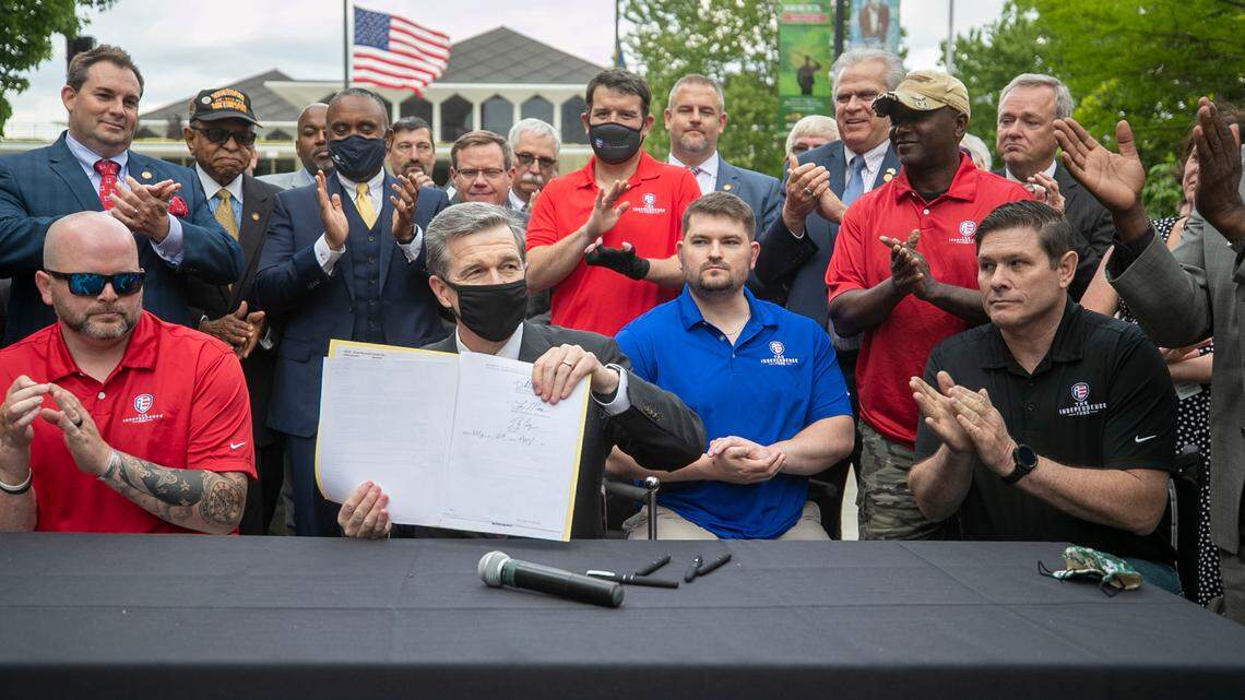 Flanked by veterans and lawmakers, North Carolina Governor Roy Cooper signs House Bill 138/Senate Bill 132, to declare April 24 North Carolina’s Wounded heroes Day during a ceremony on the Bicentennial Plaza on Wednesday, April 21, 2021 in Raleigh, NC.