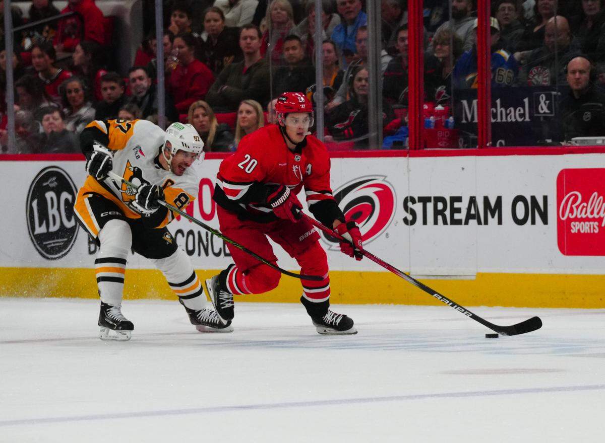 Jan 13, 2024; Raleigh, North Carolina, USA; Carolina Hurricanes center Sebastian Aho (20) skates with the puck against Pittsburgh Penguins center Sidney Crosby (87) during the first period at PNC Arena. Mandatory Credit: James Guillory-USA TODAY Sports