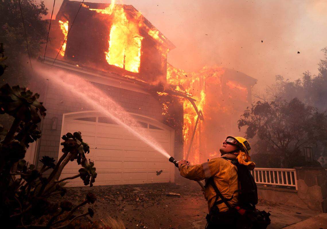 Firefighters battle a house fire off Bollinger Drive in Pacific Palisades, California, after a brush fire spread quickly with heavy winds on Tuesday, Jan. 7, 2025. (Wally Skalij/Los Angeles Times/TNS)