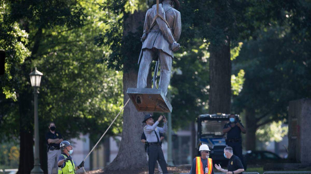 The Confederate soldier statue atop the historic Confederate monument on the west side of the North Carolina State Capital grounds is removed by a crane on Sunday, June 21, 2020 in Raleigh, N.C.