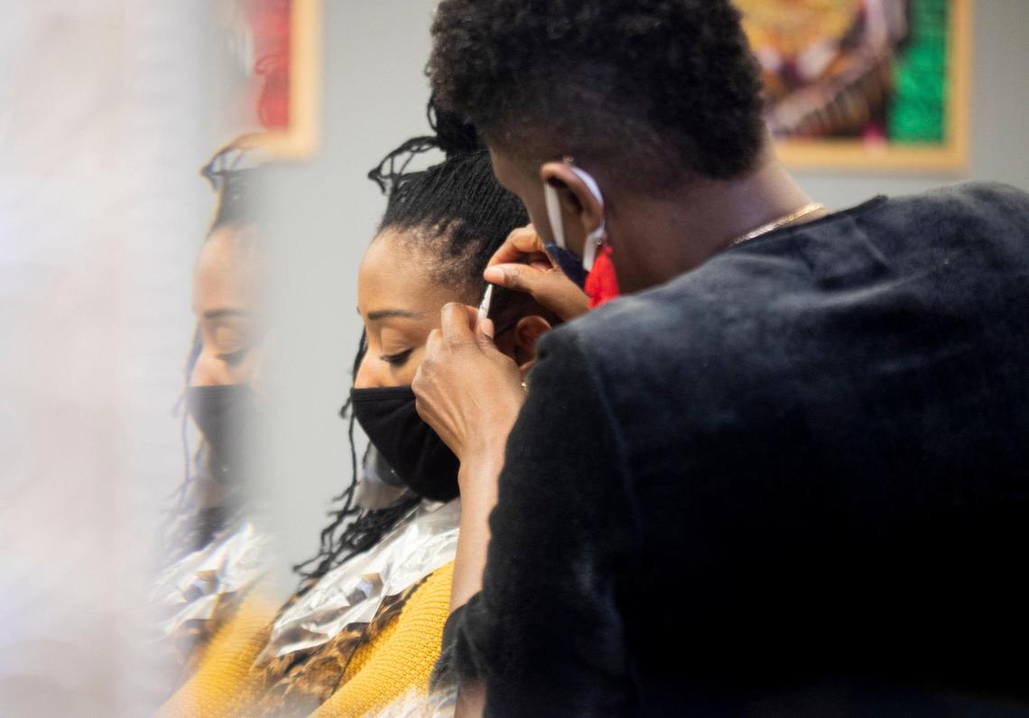 Denise Browning, left, has her Sisterlocks retightened in The Barbee Shop by Wendi Barbee, right, on Friday, Jan. 15, 2021, in Durham, N.C.
