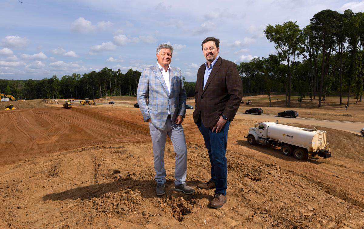 Todd Saieed, left, and Ven Poole pose Tuesday, June 7, 2022, on the site where The Exchange Raleigh is being built. The new 40-acre development will include office space, retail and restaurant space, a hotel, and residential units.