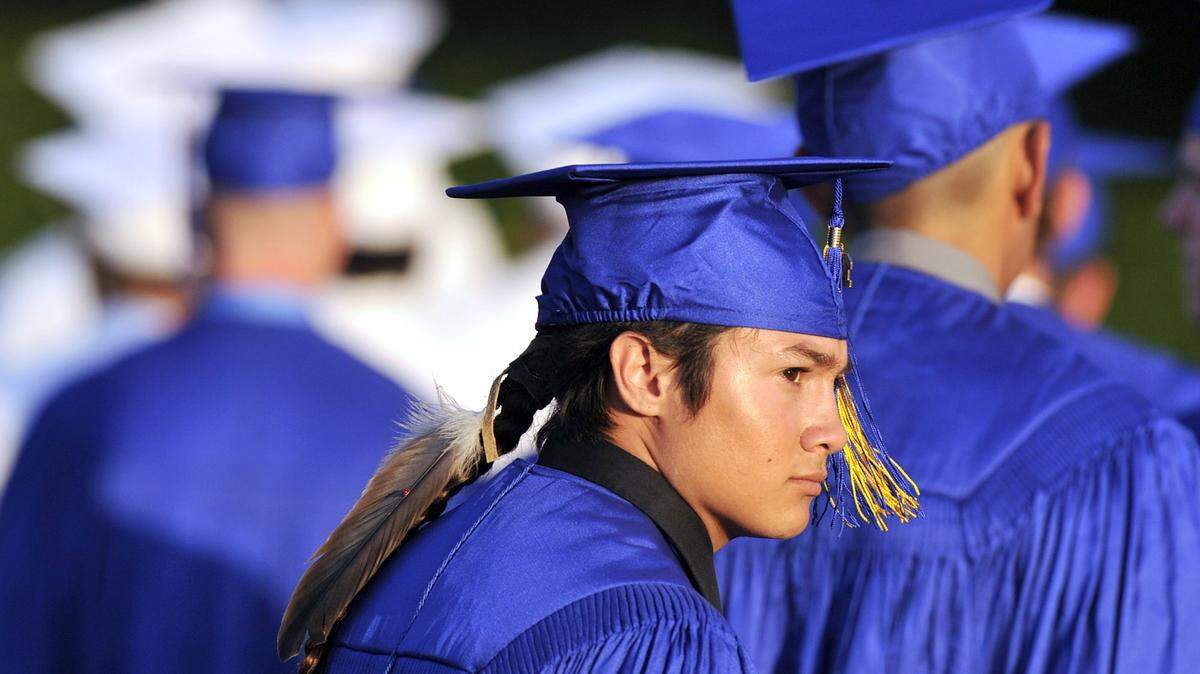 Christian Titman, center, looks into the sun wearing a feather as he and his graduating class enter Clovis High’s Lamonica Stadium in June 2015 in Clovis, Calif. North Carolina lawmakers could require public schools to allow Native American students to wear cultural signifiantly objects at graduation.