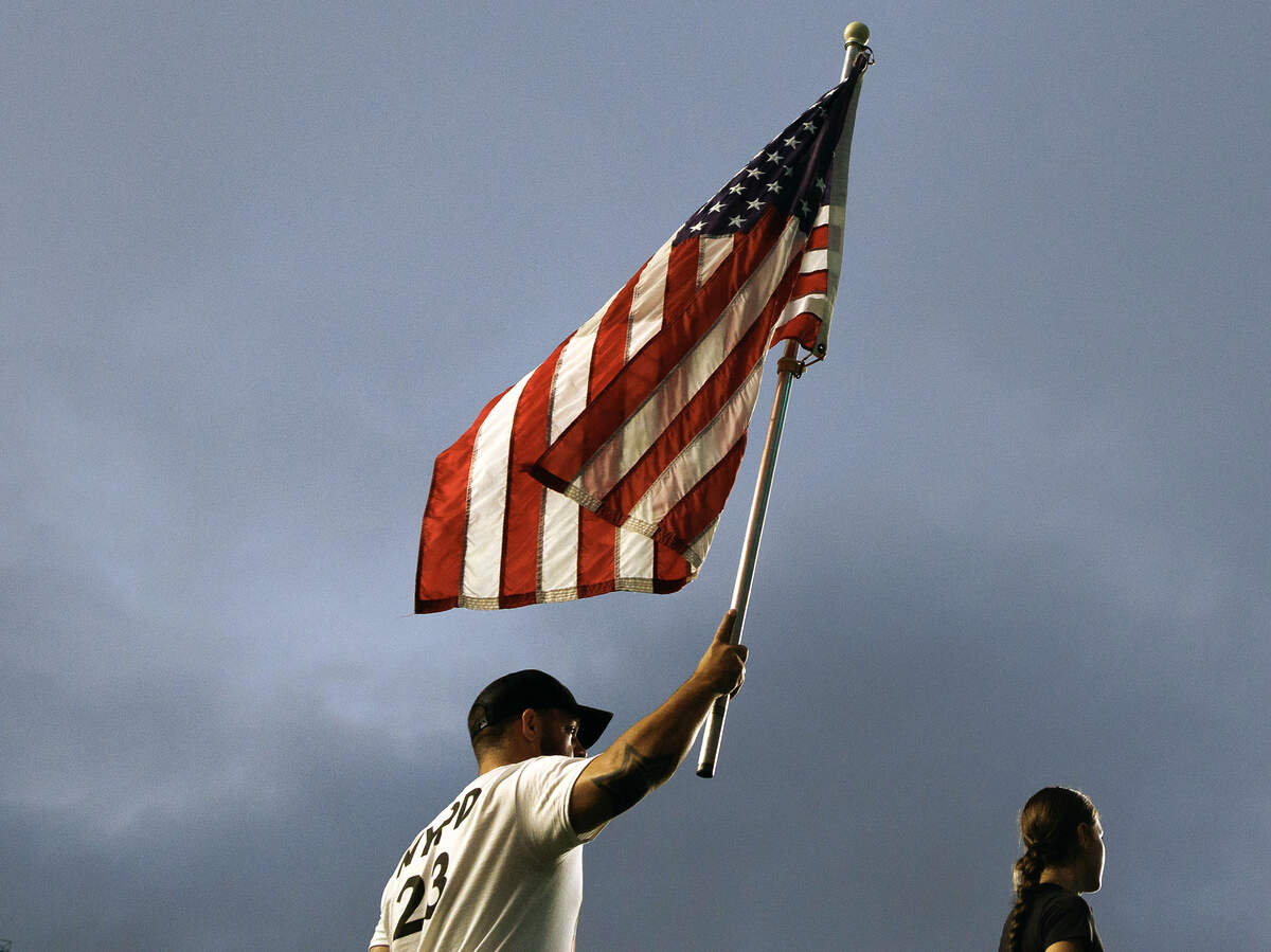 A person holds an American flag aloft during an event at Kenan Memorial Stadium on Thursday, Sept. 11, 2025, to honor those who lost their lives during attacks of Sept. 11, 2001.