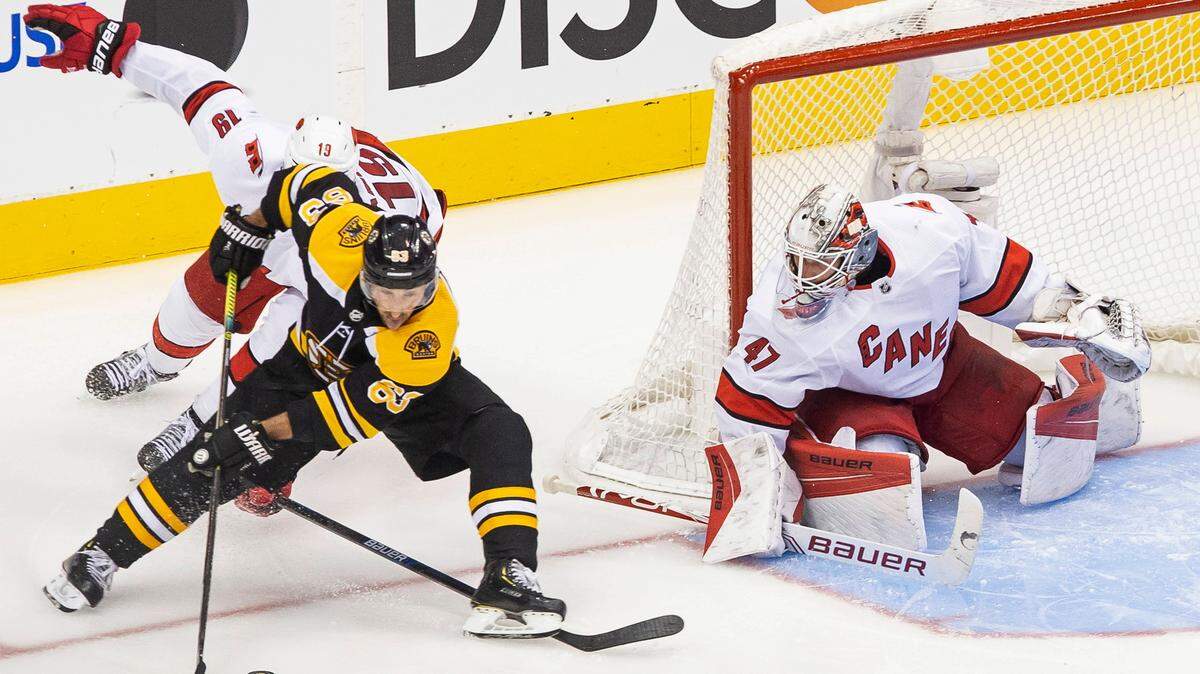Boston Bruins’ Brad Marchand (63) protects the puck from Carolina Hurricanes’ Dougie Hamilton (19) as Hurricanes goaltender James Reimer (47) waits for the shot during the third period of an NHL Eastern Conference Stanley Cup hockey playoff game in Toronto, Thursday, Aug. 13, 2020. (Chris Young/The Canadian Press via AP)