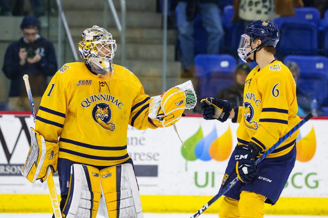 Quinnipiac freshman defenseman Charles-Alexis Legault taps gloves with goalie Yaniv Perets during a game against Yale during the 2022-23 ECAC hockey season.
