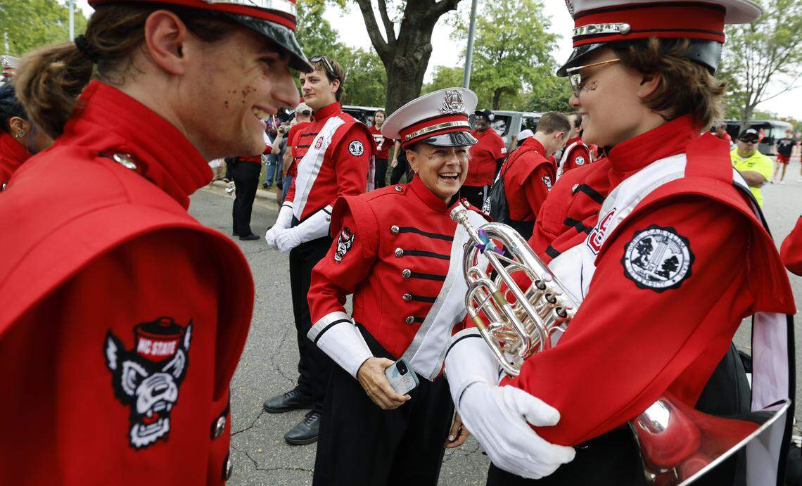 N.C. State Marching Band member Lois Roegge, 58, center, laughs while talking with bandmates before N.C. State’s game against Virginia Tech at Carter-Finley Stadium in Raleigh, N.C., Saturday, Sept. 27, 2025.