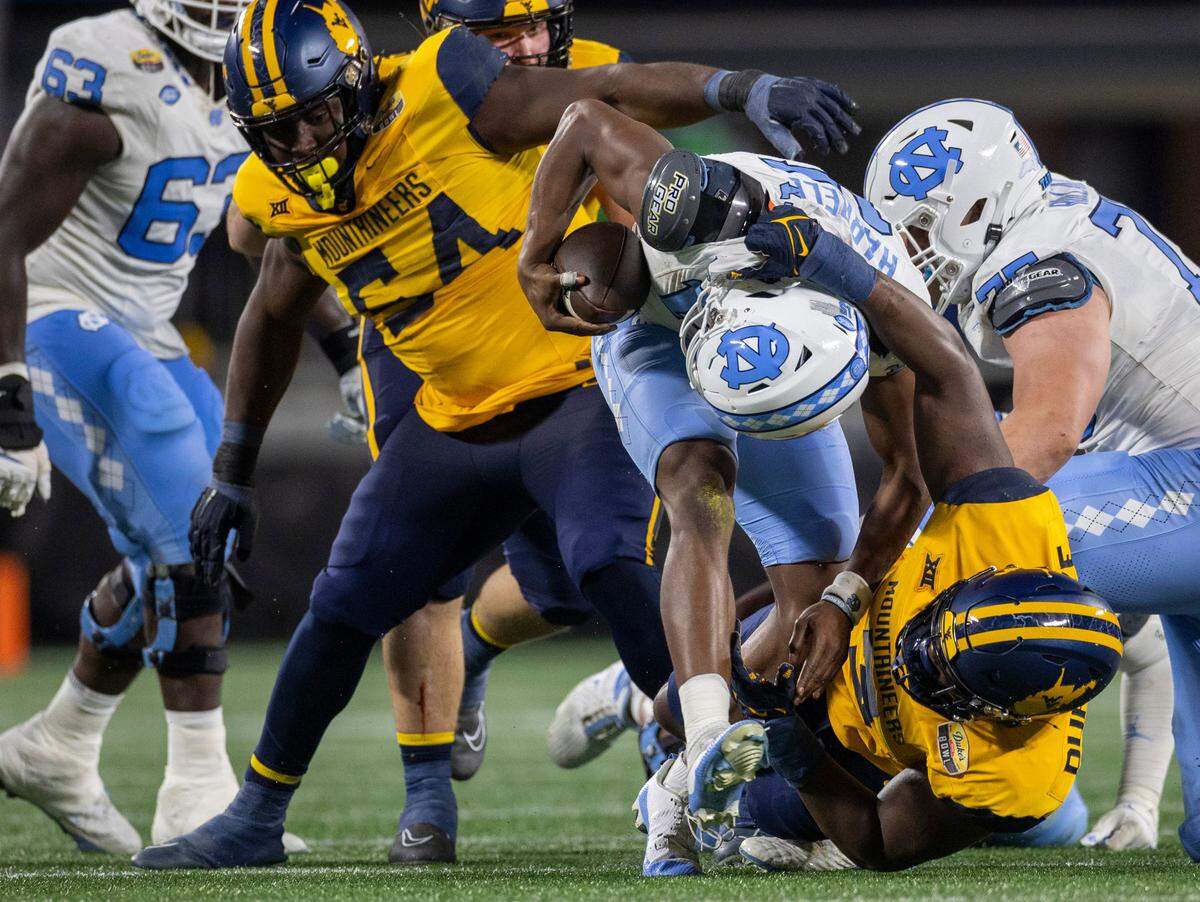North Carolina quarterback Conner Harrell (15) is sacked for a eight-yard loss in the third quarter by West Virginia’s Tomiwa Durojaiye (3) during the Duke’s Mayo Bowl on Wednesday, December 27, 2023 at Bank of American Stadium in Charlotte, N.C. The Mountaineers held the Tar Heels scoreless in the second half and rolled to a 30-10 victory.