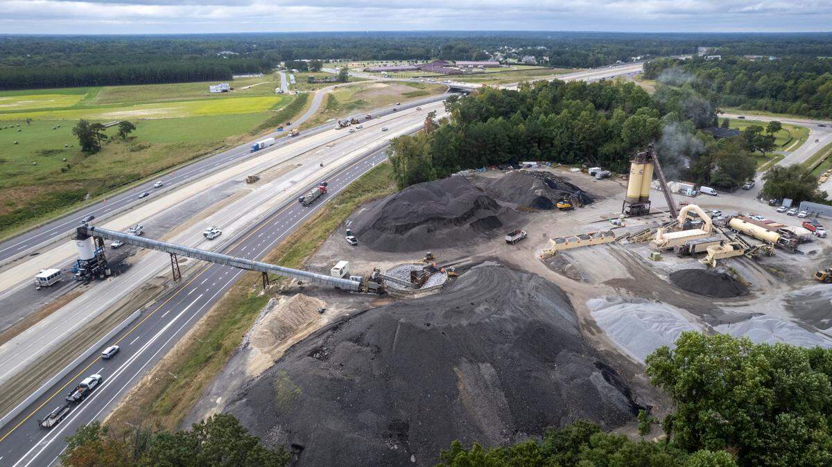 A conveyor system carries asphalt over the eastbound lanes of Interstate 40 near the N.C. 42 interchange on Sept. 27, 2023. The conveyor moves asphalt from a plant off Cleveland Road.