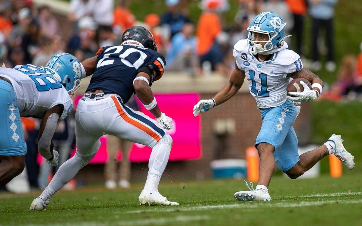 North Carolina’s Josh Downs (11) looks for running room after a reception from quarterback Drake Maye on an 11-yard gain against Virginia’s Jonas Saker (20) in the second quarter on Saturday, November 5, 2022 at Scott Stadium in Charlottesville, Va.