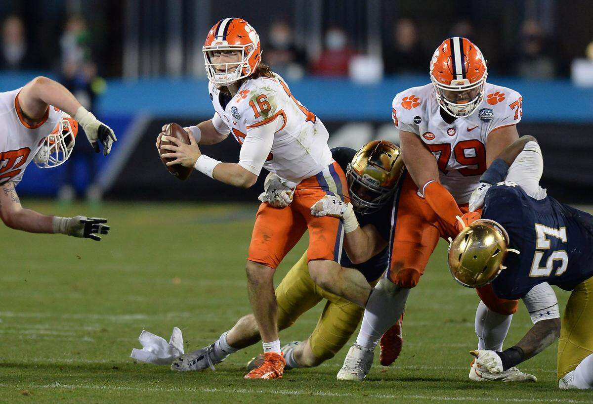 Clemson Tigers quarterback Trevor Lawrence continues to look for a receiver as a Notre Dame defender wraps him up during the ACC Championship game. Clemson defeated Notre Dame 34-10 to win the championship at Bank of America Stadium in Charlotte, NC on Saturday, December 19, 2020.  