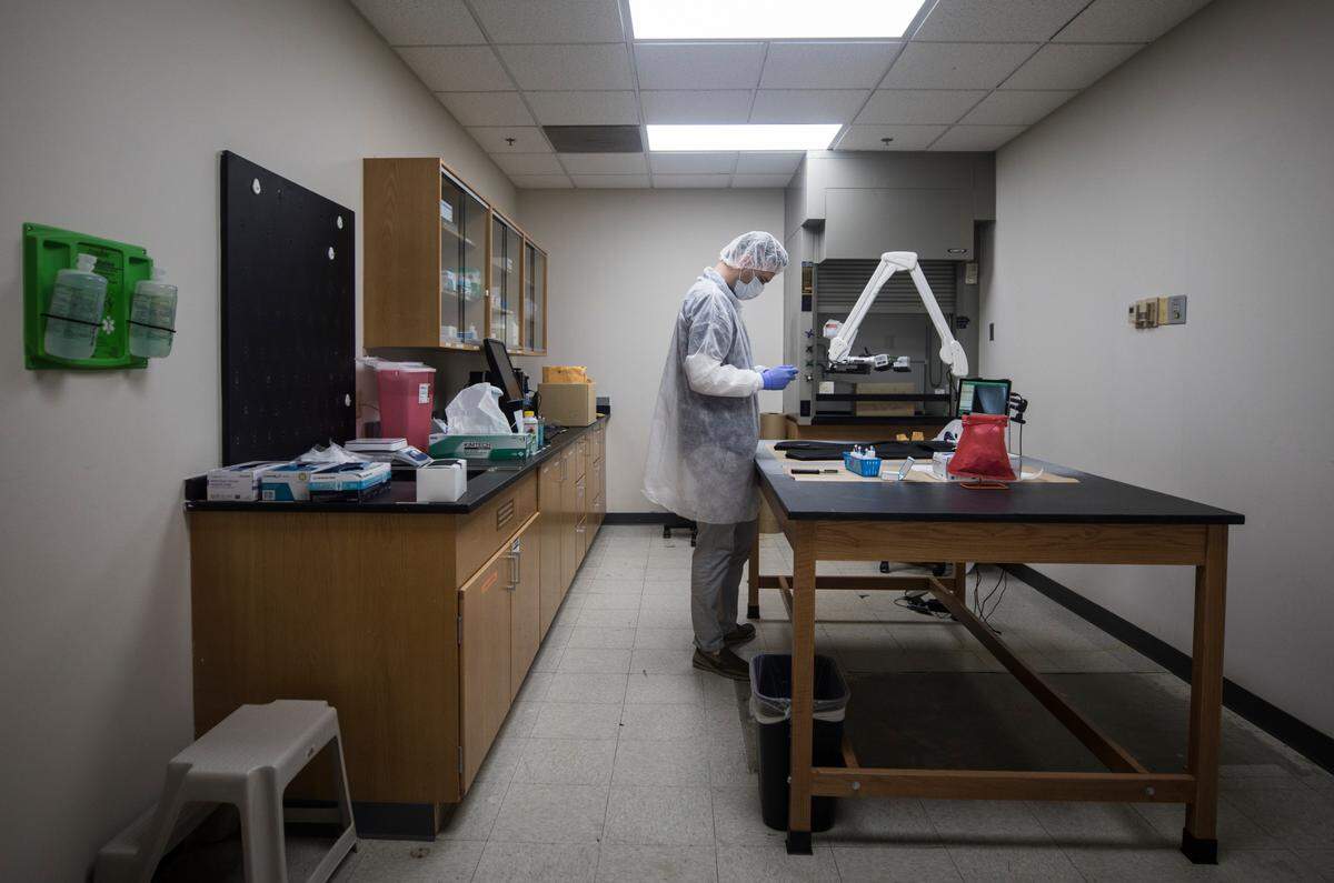 Forensic biologist Andrew Walker examines bulk evidence for the possible presence of bodily fluids at the State Crime Lab in Raleigh, N.C. on Sept. 30, 2021.