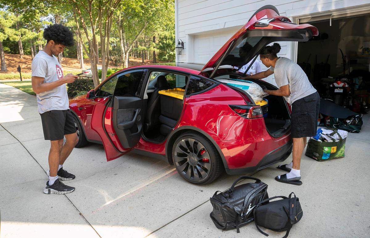 Jarin Stevenson check his phone as his parents Jarod and Nicole Stevenson help their son load his car for the trip to Tuscaloosa, Ala., on Wednesday, June 28, 2023 at their home in Chapel Hill, N.C. Stevenson will enroll in summer classes and begin training for the Crimson Tide’s 2023-24 basketball season. One week ago Stevenson, one of the top high school basketball players in North Carolina announced he was reclassifying, and committed to play for the University of Alabama. 