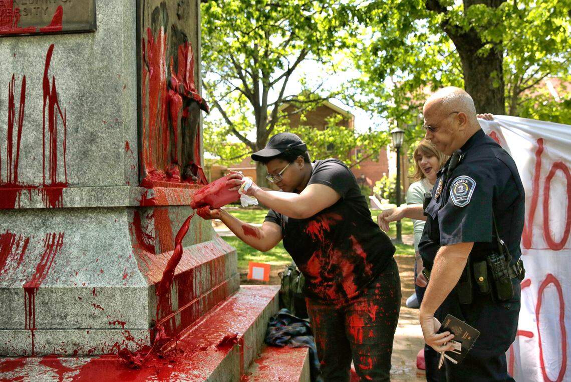 UNC-Chapel Hill student Maya Little, center, pours a mixture of her own blood and paint on the Silent Sam Confederate statue in defiance of a UNC-Chapel Hill police officer's order to stop on the campus of UNC-Chapel Hill  in Chapel Hill, N.C., on Monday, April 30, 2018. Little was arrested following the event.