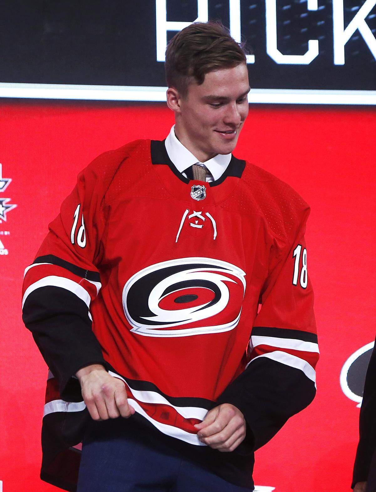 Andrei Svechnikov, of Russia, puts on a jersey after being selected by the Carolina Hurricanes during the NHL hockey draft in Dallas, Friday, June 22, 2018.