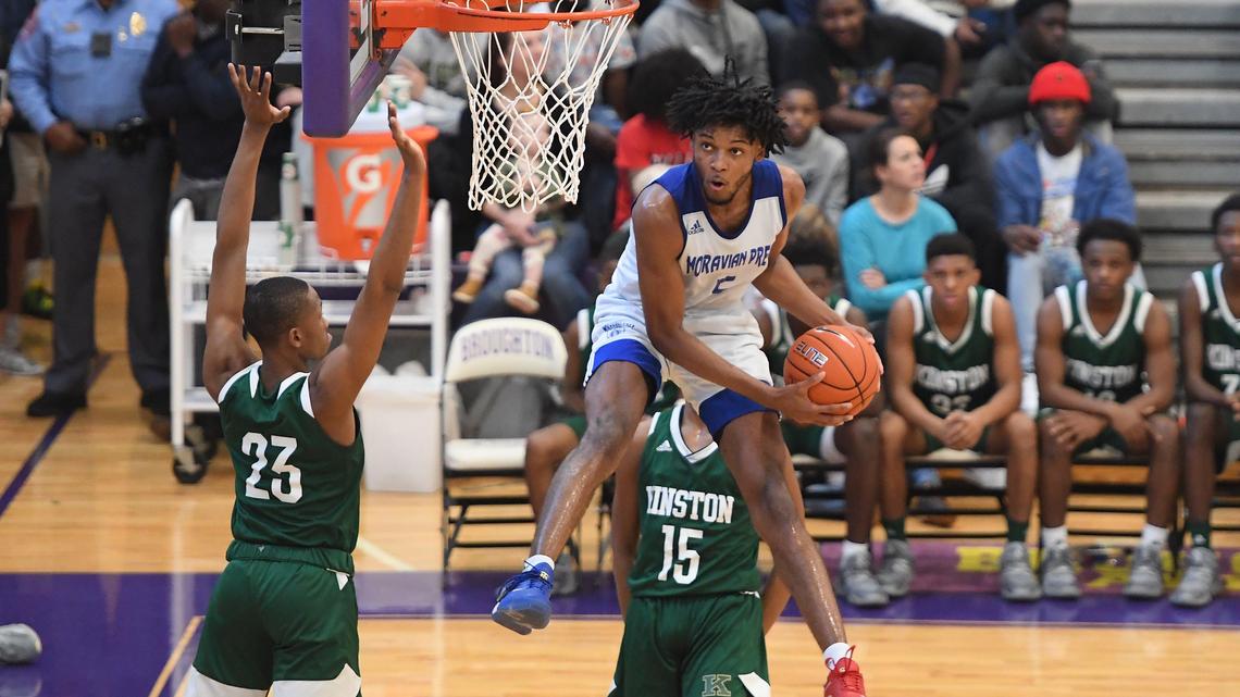 Josh Hall (5) of Moravian Prep drives to the basket against Jeremy Dixon (23) and Clarence Burton (15) of Kinston. The Moravian Prep Lions played the Kinston Vikings in a boys basketball game that was part of the John Wall Holiday Invitational on December 26, 2019.