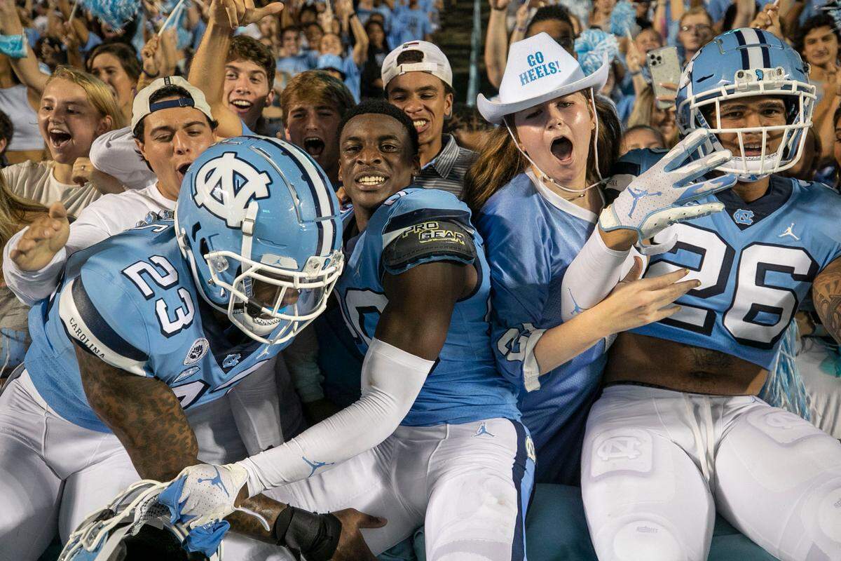 North Carolina players Power Echols (23), Tony Grimes (20) and Trevion Stevenson (26) jump into the student section to designate the start of the fourth quarter of play against Virginia on Saturday, September 18, 2021 at Kenan Stadium in. Chapel Hill, N.C.