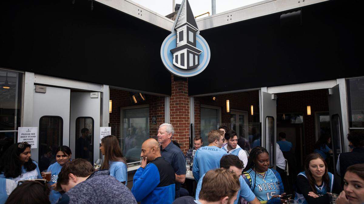 A crowd of mostly UNC fans gather on the balcony at Top of the Hill in Chapel Hill, N.C. to watch their team face off with their rival, Duke, in New Orleans in a historic Final Four game on Saturday, April 2, 2022.