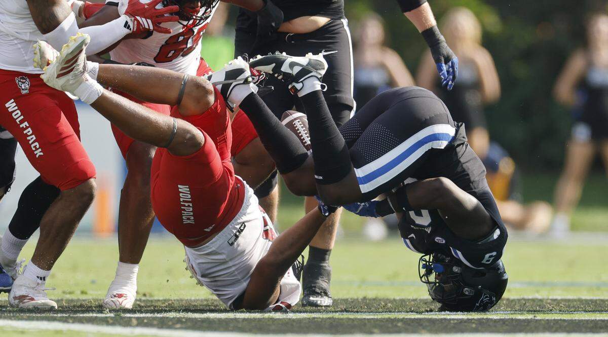 The forward progress of Duke running back Jaquez Moore (9) was stopped before he fumbled while being hit by N.C. State defensive end Travali Price (13) during the first half of N.C. State’s game against Duke at Wallace Wade Stadium in Durham, N.C., Sat. Sept. 20, 2025
