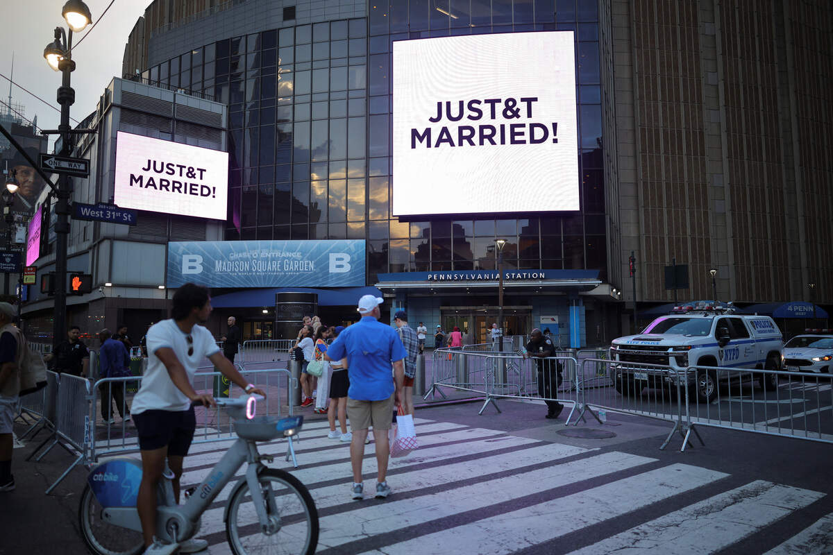 People gather near screens displaying messages referencing Taylor Swift and Travis Kelce outside Madison Square Garden, the venue for their reported wedding celebrations, in New York, U.S., July 3, 2026.