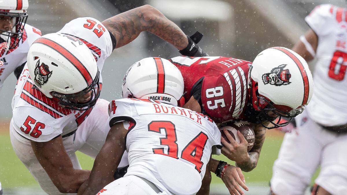 Anthony Smith runs the ball under pressure from Zyun Reeves (56) and Kamal Bonner (34) during N.C. State football’s spring game at Carter-Finley Stadium on Saturday, April 8, 2023, in Raleigh, N.C.