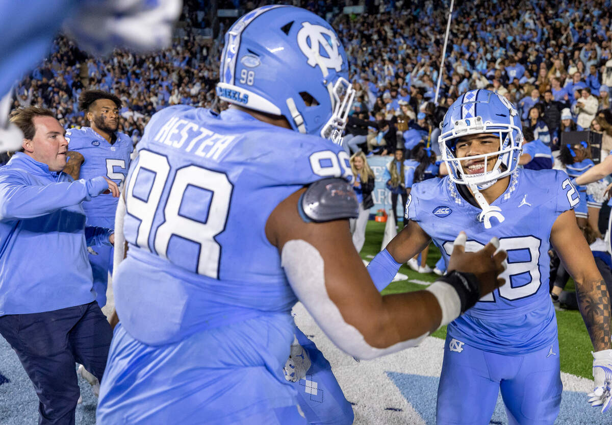 North Carolina’s (98) Kevin Hester Sr. and his teammates swarm around Armani Chatman (9) following the Tar Heels’ 47-45 double overtime victory over Duke on Saturday, Nov. 11, 2023 at Kenan Stadium in Chapel Hill, N.C.