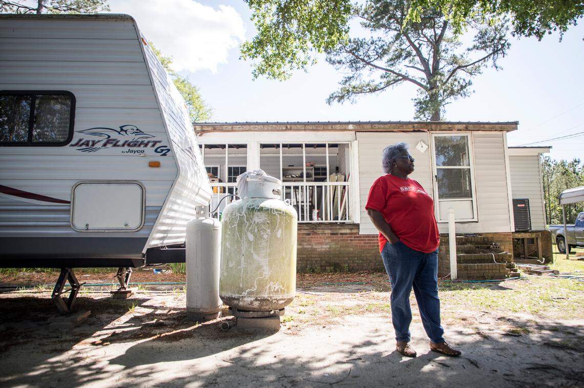 Jacqueline Hand stands outside her home next to the travel trailer she and her family are living in off Whitestocking Road near Burgaw, N.C., on Monday, April 27, 2020. Hand’s home was inundated with flood waters during Hurricane Florence and she and her family have yet to move back in almost two years later. Delays in permitting and difficulty securing contractors prevented repairs for almost a year, therefore volunteer groups were a huge help. However, now that the renovation is nearing the finish line, COVID-19 has forced volunteer organizations to pull people out of the area.
