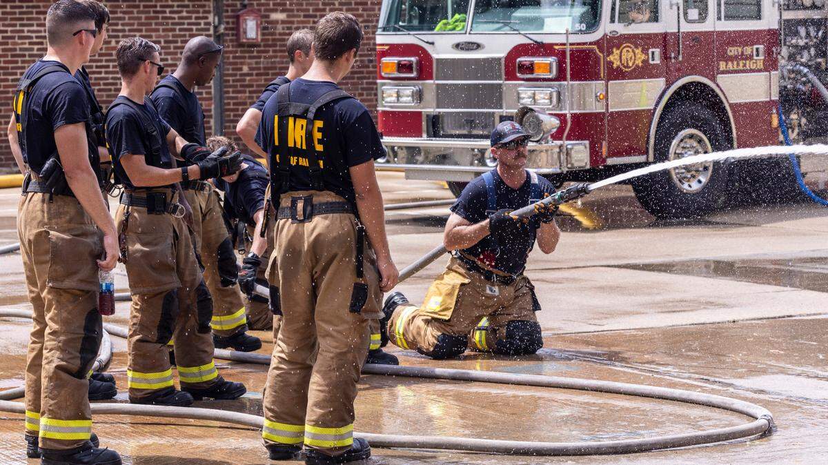 Captain Greg Wheeler of the Raleigh Fire Department, kneeling, leads a demonstration for Raleigh firefighter recruits at the Keeter Training Center in Raleigh Monday, July 25, 2022. The Raleigh Fire Department has 65 vacancies and a current academy class with 55 graduates expected this fall.