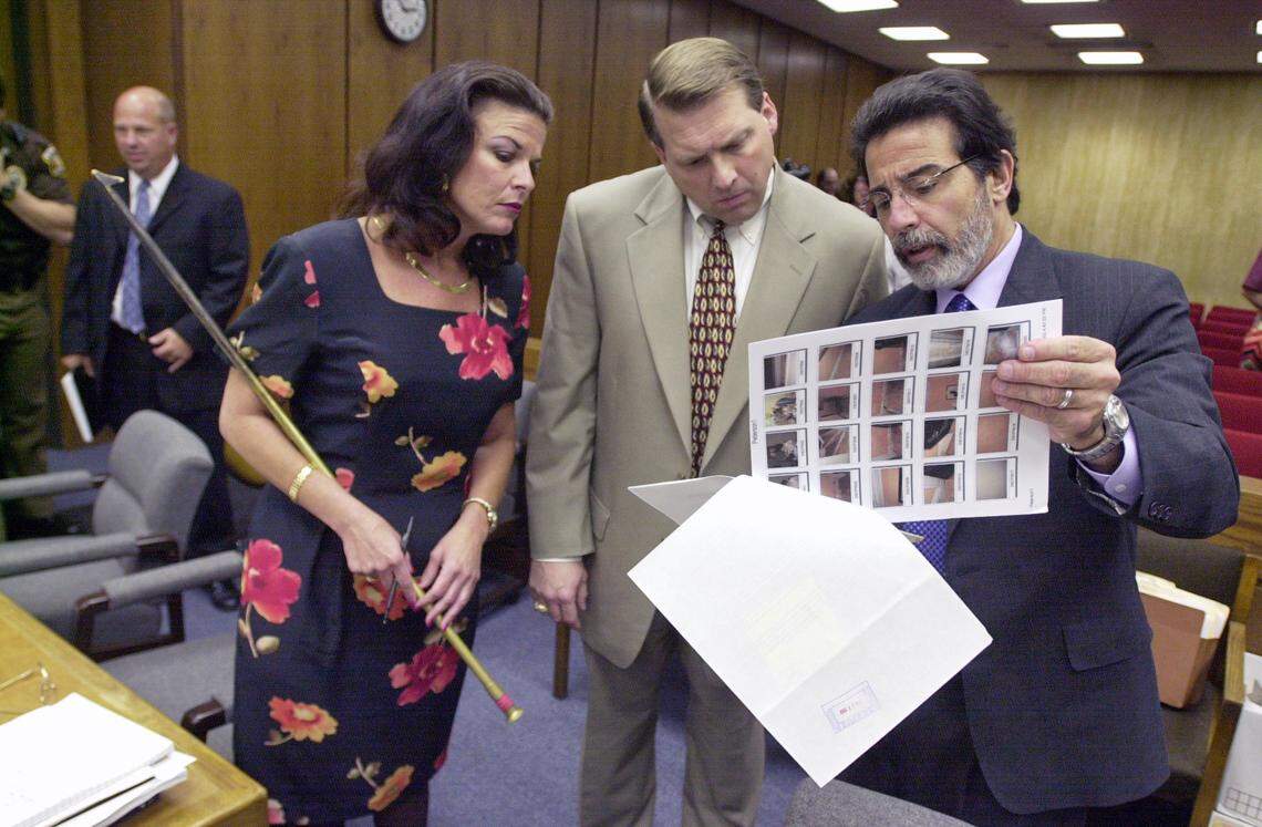 Durham prosecutor Freda Black (left), holds prosecution evidence, the brass blow poker, while fellow prosecutor Jim Hardin, center, examines evidence with lead defense attorney David Rudolf during day 41 of the 2003 trial of Michael Peterson