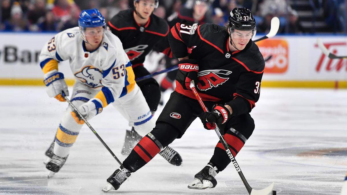 Carolina Hurricanes right wing Andrei Svechnikov (37) skates the puck away from Buffalo Sabres left wing Jeff Skinner (53) during the first period of an NHL hockey game in Buffalo, N.Y., Wednesday, Feb. 1, 2023. (AP Photo/Adrian Kraus)