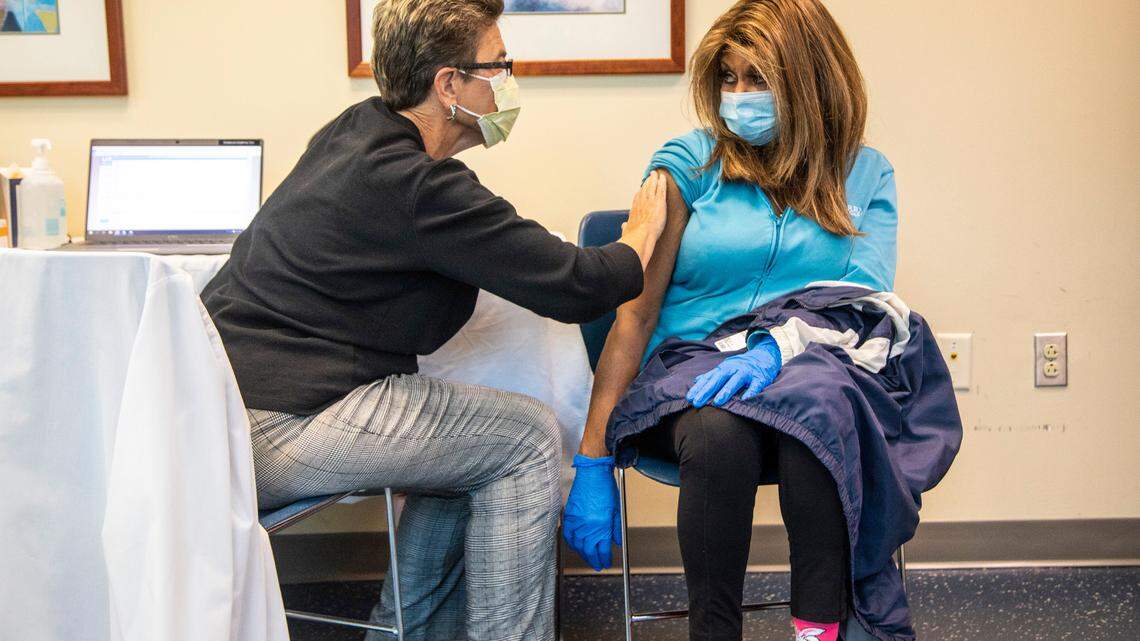 Robin Deal, a retired registered nurse, left, prepares to administers a flu shot to Cheyenne Cravencrozier at Rex Wellness Center of Cary on Thursday, Oct. 14, 2021.