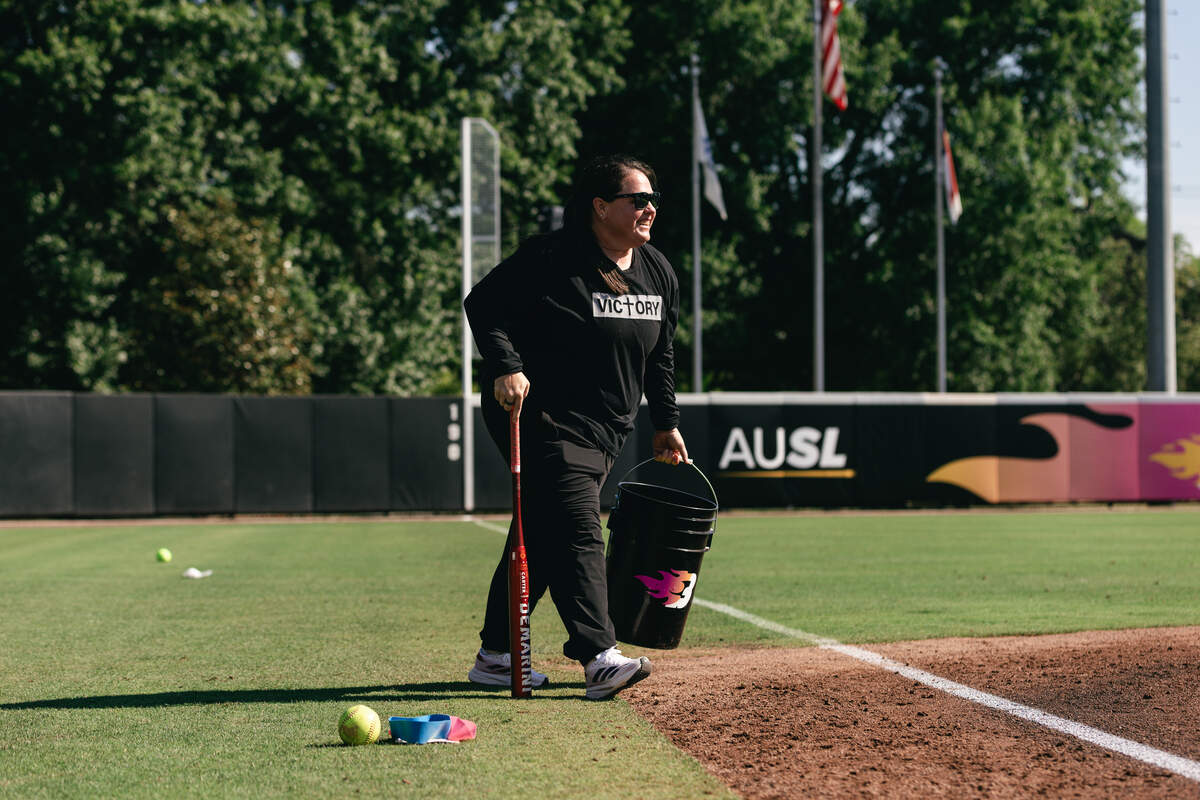 Carolina Blaze associate head coach Lindsay Leftwich carries a bat and bucket of softballs onto the field at Smith Family Stadium in Durham, North Carolina. Leftwich also serves as the N.C. State head softball coach.