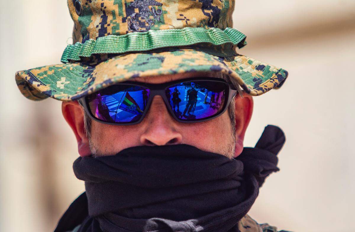 Adam Smith, an organizer with the ReOpen NC group, wears a face covering while demonstrating with group of about a half dozen mostly armed protesters affiliated with the Facebook group Blue Igloo as they marched in downtown Raleigh Saturday, May, 16, 2020.
