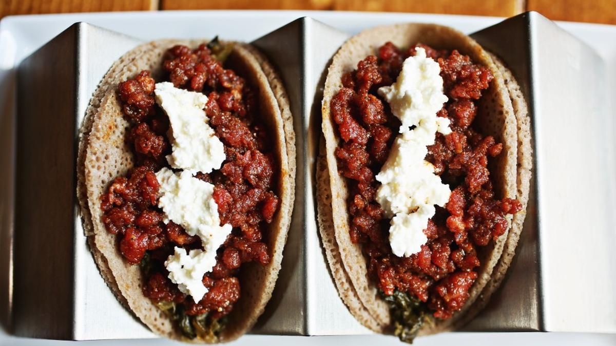 
Goorsha's kitfo presentation calls to mind tacos with injera cut into taco size rounds, folded around kitfo and spinach, and topped with crumbles of Ethiopian fresh cheese. They're even folded taco style, and served two to an order on a taco tray.

