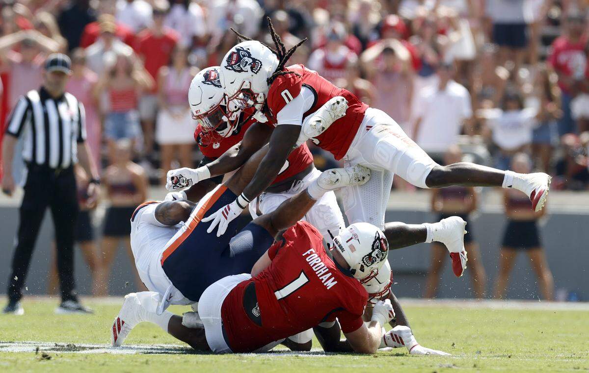N.C. State’s Caden Fordham (1) and Sean Brown (0) tackle Virginia tight end Dakota Twitty (9) during the first half of N.C. State’s game against Virginia at Carter-Finley Stadium in Raleigh, N.C., Sat. Sept. 6, 2025.